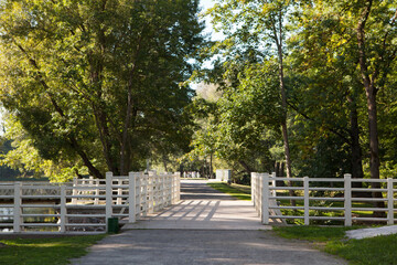 Beautiful white wooden pedestrian bridge over the river in a summer picturesque park.