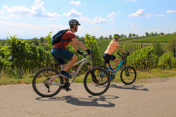 Fototapeta na wymiar Symbolbild: Junges Paar bei einer Fahrradtour in den Weinbergen