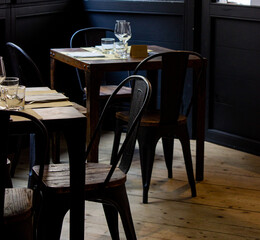 Detail of a retro style restaurant. Laid tables and chairs. Dark image