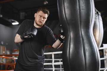Fototapeta na wymiar Man in a black t-shirtg boxing in a gym