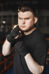 Obraz na płótnie Canvas Man in a black t-shirtg boxing in a gym