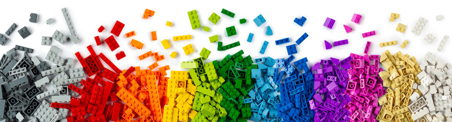 top view of wide pile various colorful rainbow colored stackable plastic toy bricks isolated white panorama background.. childhood education construction concept