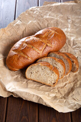 Bread and bakery in craft paper on brown wooden background.