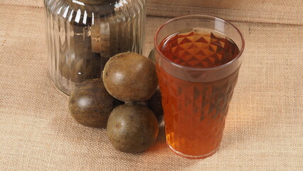 Monk fruit or Luo Han Guo. Dried fruits for healthy sweetener drink. Natural herbal remedy and glass bottle background. Monk fruit drink for who concern health and sugar substitute. 