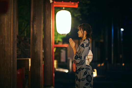 神社でお祈りをする浴衣の女性
