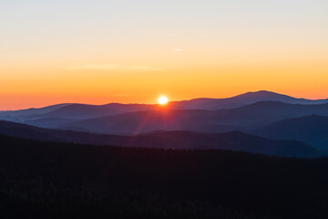 Beautiful and bright sunrise in the mountains. The sun's rays are breaking through from the tops of the misty mountains