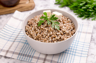 Freshly cooked buckwheat porridge in a plate on a gray background.
