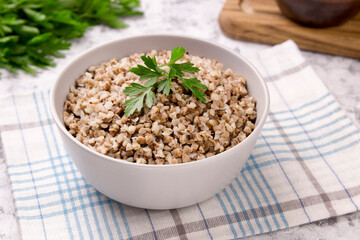 Freshly cooked buckwheat porridge in a plate on a gray background.