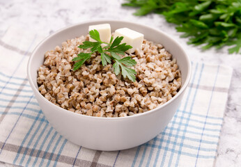 Freshly cooked buckwheat porridge in a plate on a gray background.