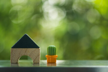 Miniature small made from wooden toy blocks with miniature cactus on a nature background.