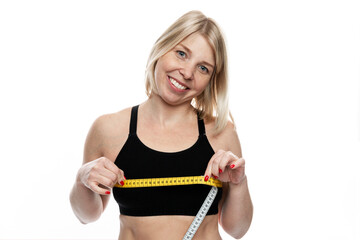 Smiling woman with a measuring tape on her chest. Pretty blonde in a sporty black top. Sports,...