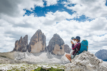 Young mom with baby boy travelling with backpack. Mother on hiking adventure with child, family trip in mountains. Vacations journey with infant National Park Tre Cime di Lavaredo, Dolomites, Italy