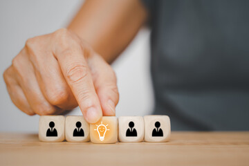 human's hand holding bright light bulb icon on wooden cube for leadership , brainstorming concept