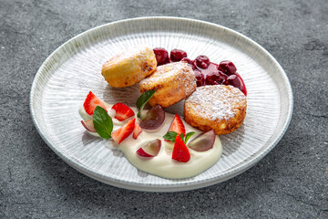 Sweet cottage cheese pancakes with jam and berries. Ready menu for the restaurant. Neutral gray blue textured background