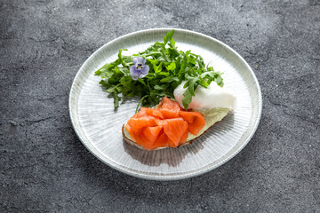 Bruschetta with salmon, poached egg and cheese. Ready menu for the restaurant. Neutral gray blue textured background