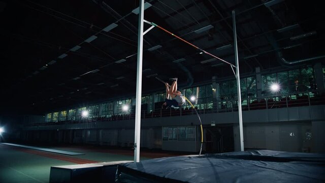 Pole Vault Jumping: Professional Male Athlete Running with Pole Successfully Jumping over Bar, Celebrating Victory and Best Results after Standing Up. Dramatic Color, Cinematic Slow Motion, Wide Shot