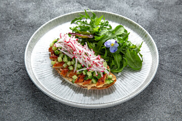 Bruschetta with smoked eel, cucumber and radish. Ready menu for the restaurant. Neutral gray blue textured background