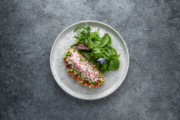 Bruschetta with smoked eel, cucumber and radish. Ready menu for the restaurant. Neutral gray blue textured background
