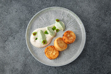 Healthy breakfast. Cottage cheese pancakes with cheese and sour cream sauce. Ready menu for the restaurant. Neutral gray blue textured background