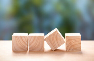 Four wooden blocks on wooden table with blurred green background.