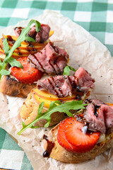 Italian Appetizer Bruschetta with roasted tomatoes, mozzarella cheese, garlic and herbs served over green tablecloth.