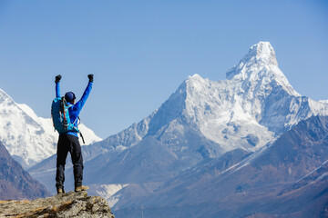 Hiker cheering elated and blissful with arms raised in the sky after hiking. Everest mountain on...