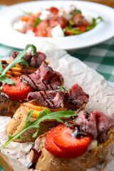 Italian Appetizer Bruschetta with roasted tomatoes, mozzarella cheese, garlic and herbs served over green tablecloth.