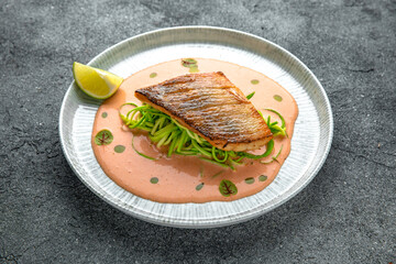 Fillet of sea bass or dorado with spinach paste. Ready menu for the restaurant. Neutral gray blue textured background