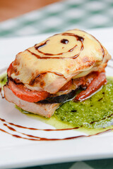 Rosemary chicken with oven-roasted ratatouille served on a white square plate over table with green plaid tablecloth.