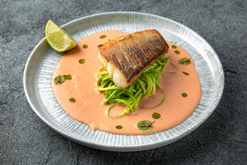 Fillet of sea bass or dorado with spinach paste. Ready menu for the restaurant. Neutral gray blue textured background