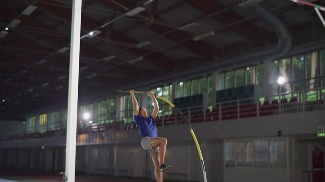 Pole Vault Jump: Professional Male Athlete Running with Pole Successfully Jumping over Bar. Determination of Champion. Championship Sport with Authentic Person and Documentary Colors. Slow Motion
