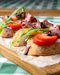 Italian Appetizer Bruschetta with roasted tomatoes, mozzarella cheese, garlic and herbs served over green tablecloth.