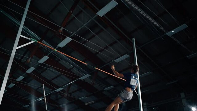 Pole Vault Jumping Championship: Professional Male Athlete Running with Pole Successfully Jumping over Bar. Determination of High Achievement Champion in Training. Low Angle Slow Motion