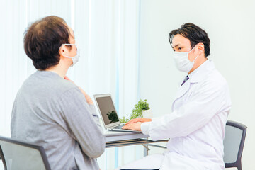 Fototapeta premium パソコンで診察するマスク姿の男性医師（のど） 
