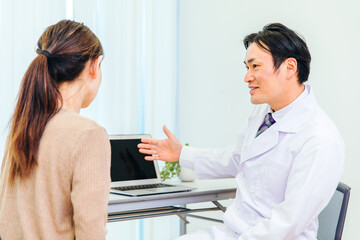 診察する男性医師と女性患者（ノートパソコン）
