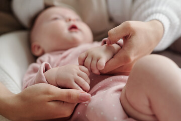 Hands of young mother calming cute baby down while lulling her after feeding