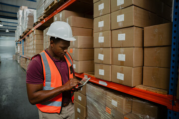 Ethnic male worker scrolling through digital tablet to locate packages sent out for delivery standing in factory shop.