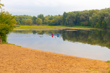 View of the beach lake with a floating boat, and the autumn forest