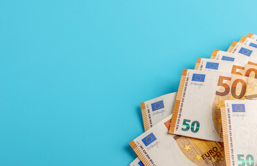 Banknotes of fifty euros on a blue background. Copy space.