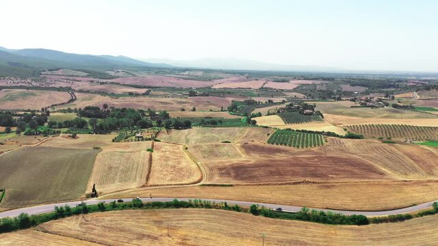 Tuscan countryside shot with drone at summer time. Aerial view of amazing wheat fields country in sunny weather, arid fields,green trees,olive trees 