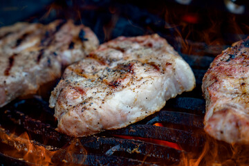 Pork steaks on the grill with flames
