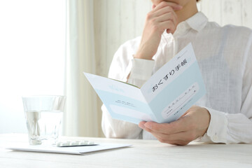 模造品のおくすり手帳を確認する女性