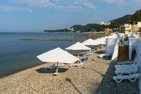 Pebble beach with open umbrellas on a sunny morning, Nebug village, Tuapse region, Russia