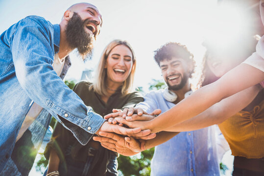 Multiracial happy young people stacking hands on top of each other - Diverse friends unity togetherness in volunteer community - Concept about college, relationship, youth and human resources