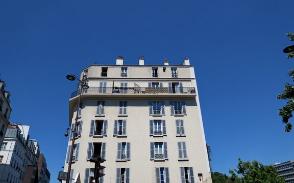 Ancien immeuble parisien. Façade blanche. Balcon  courant. Ciel bleu.