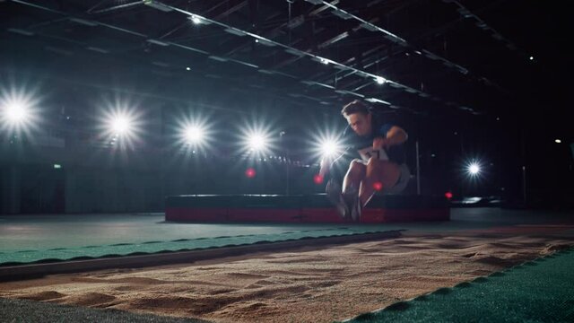 Long Jump Championship: Professional Male Athlete Running on Track and Distance Jumping. Determination, Effort, Motivation, Inspiration for Setting Sport Record. Dramatic Lights, Cinematic Slow Motion