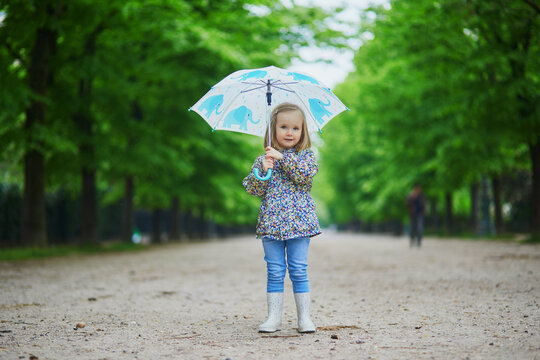 Child wearing rain boots with umbrella on a fall day