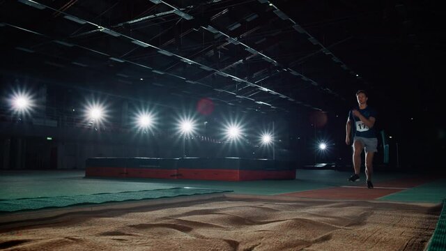Long Jump Championship: Professional Male Athlete Running on Track and Distance Jumping. Determination, Effort, Motivation, Inspiration. Dramatic Light, Dolly Shot with Cinematic Slow Motion