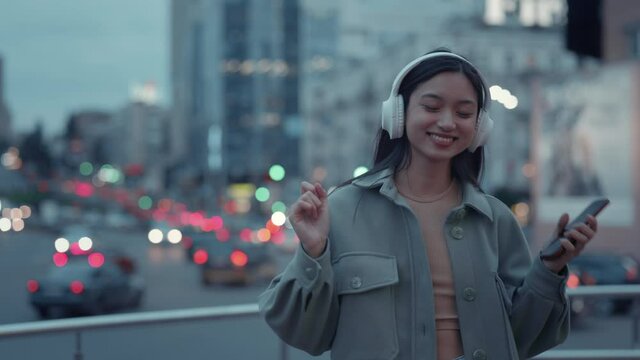 Cheerful woman walking on street in wireless headphones