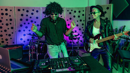 Young happy people playing music with dj mixer and guitar in house production studio - Youth...